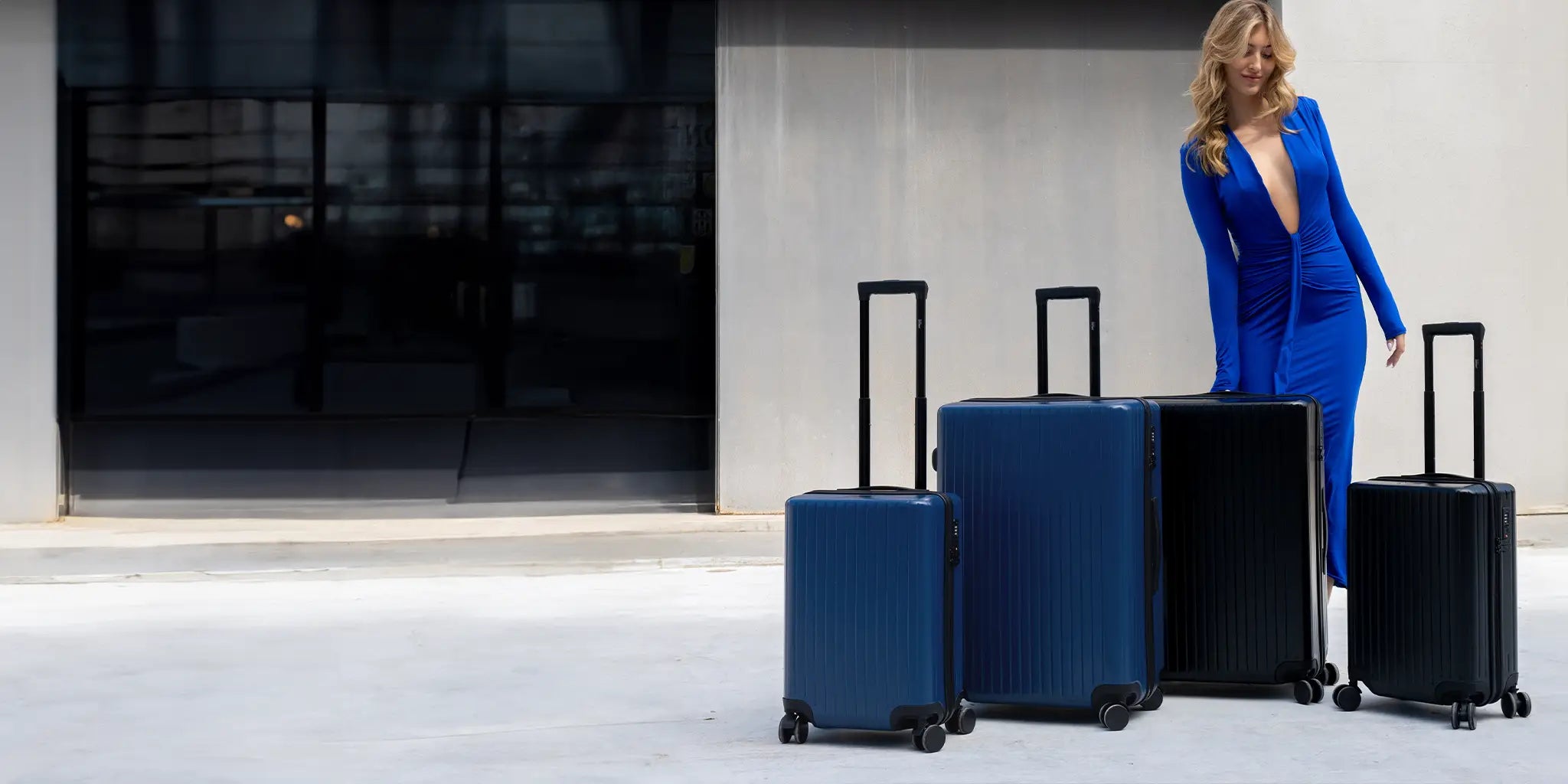 A woman in a blue dress waiting to be picked up with her 4 suitcases