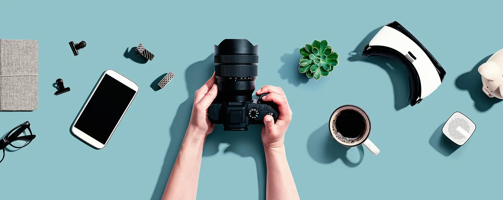 Person holding a SLR camera from above with other gadgets around