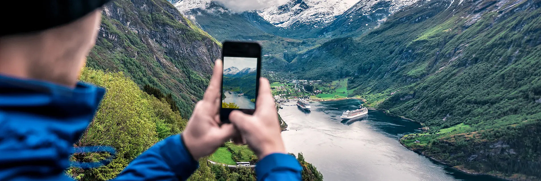 tourist takes photo of Geiranger fjord on smartphone