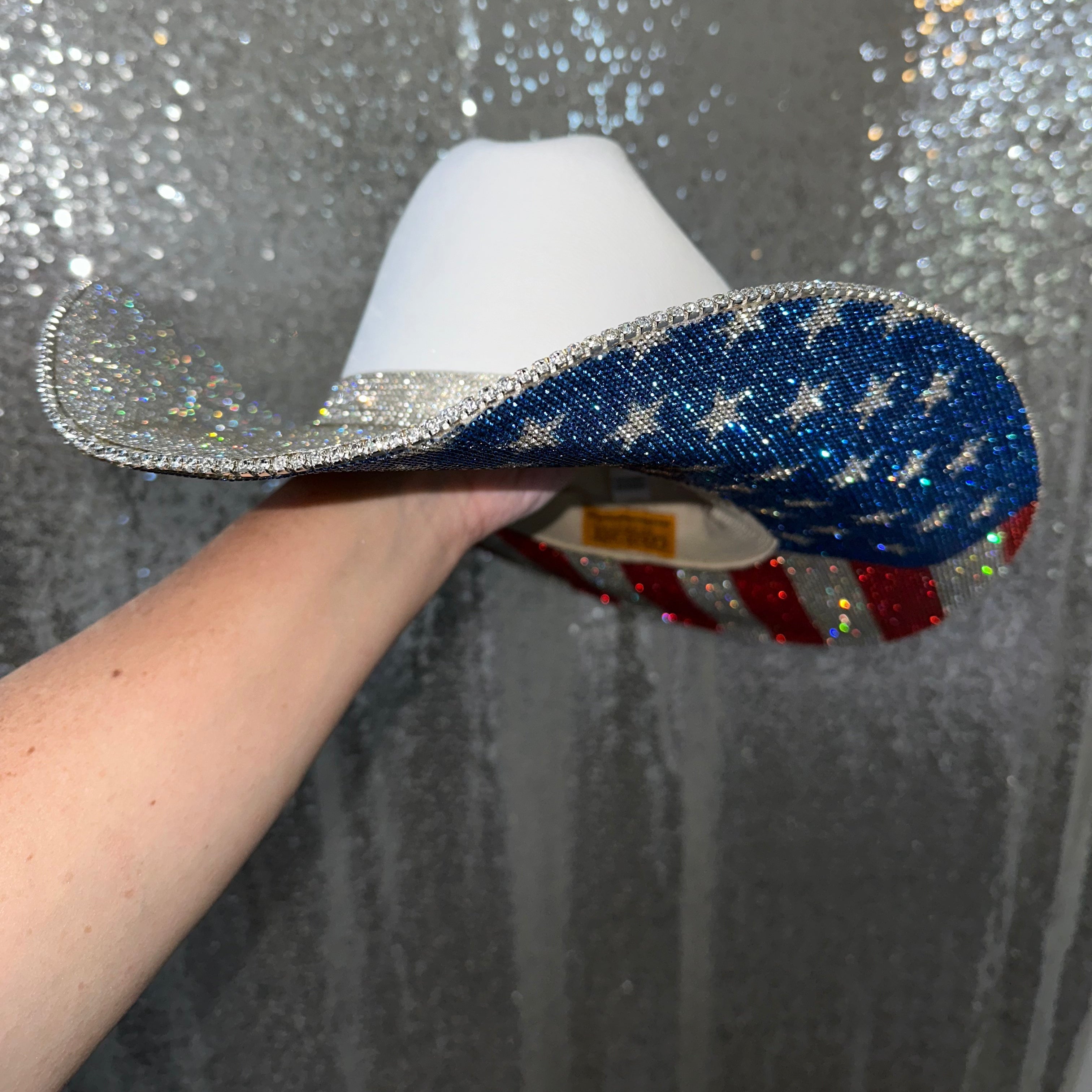 Decorative hat with blue, white, and red design held against a glittery background