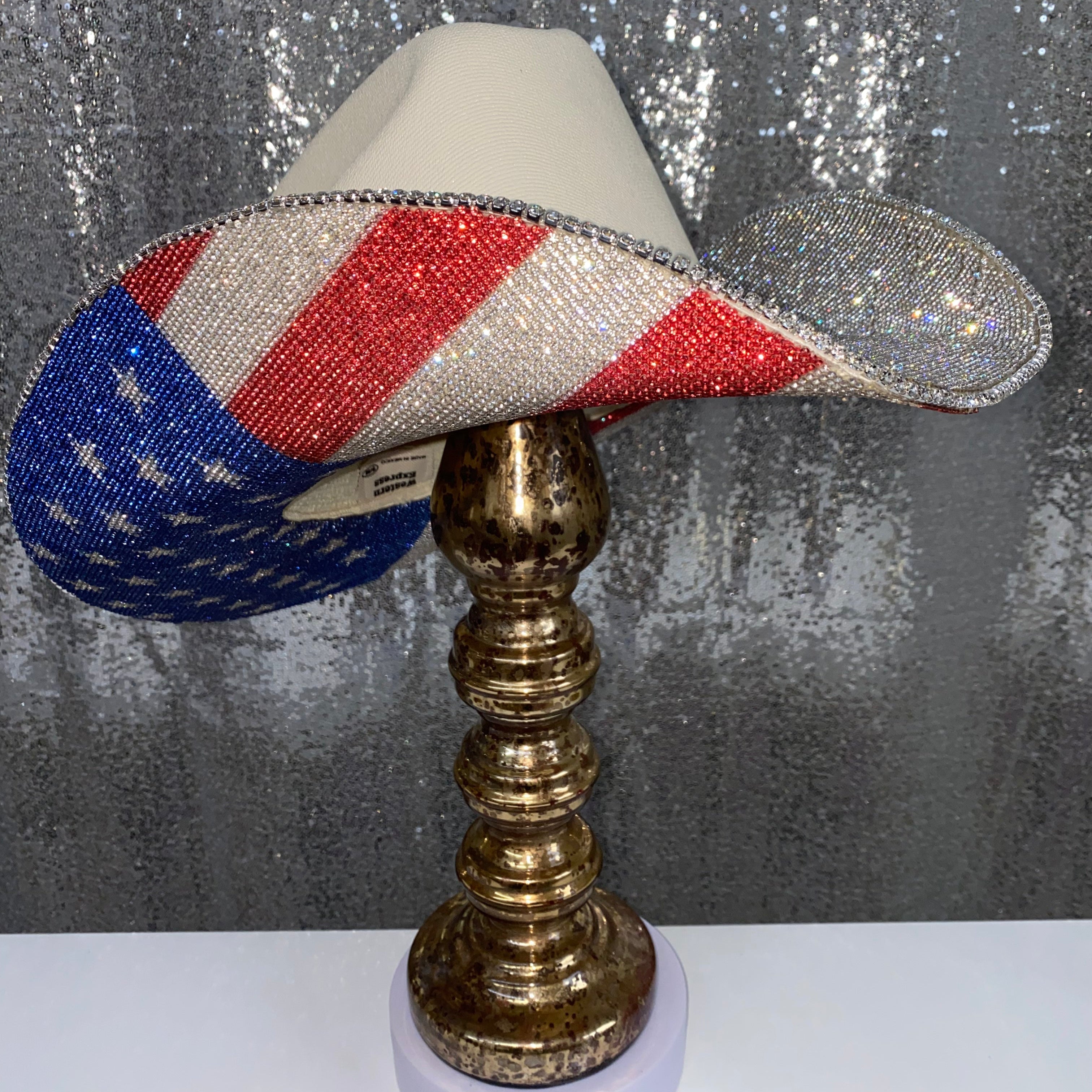 Decorative hat with American flag design on a metallic stand against a textured gray background