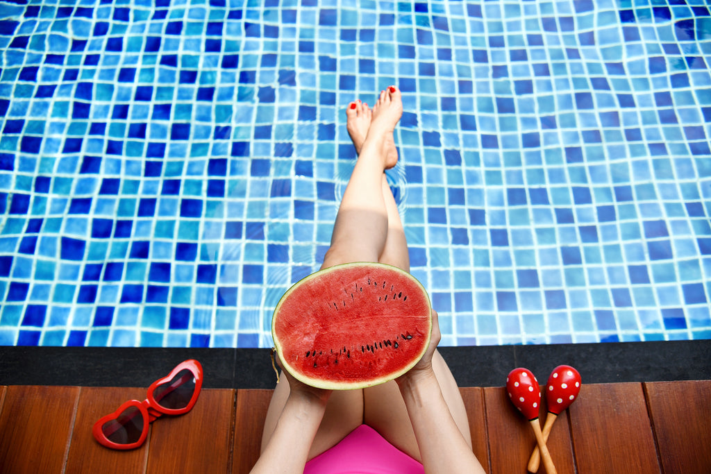 girl enjoying summer with a watermelon by the pool