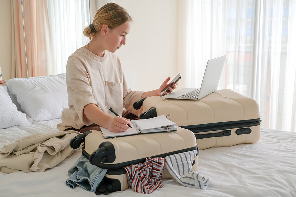 Girl with luggage planning a vacation on her phone
