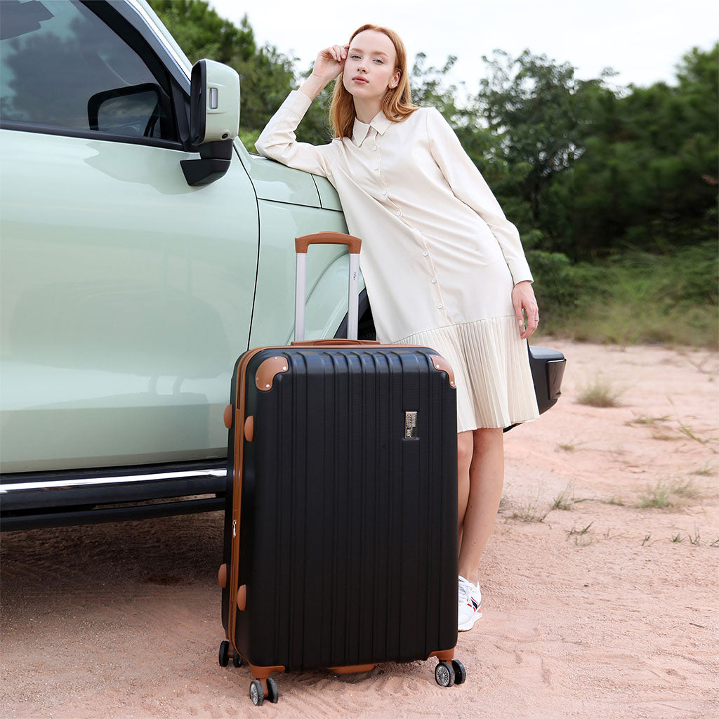 woman with a black luggage piece leaning against a car