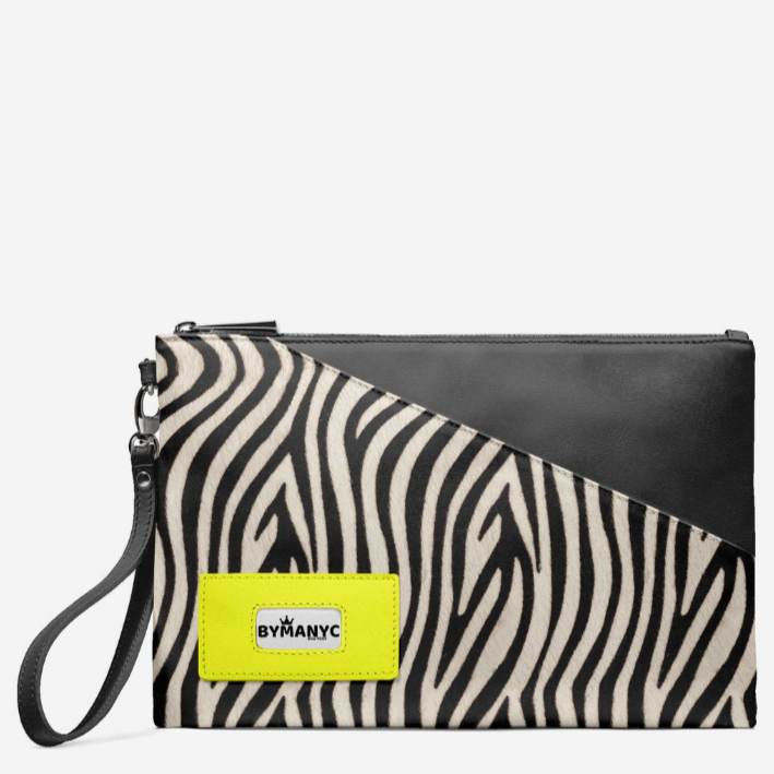 Zebra print clutch bag with black leather flap and yellow label on a white background