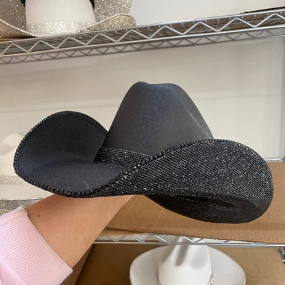 Black cowboy hat on a cardboard box with shelves in the background