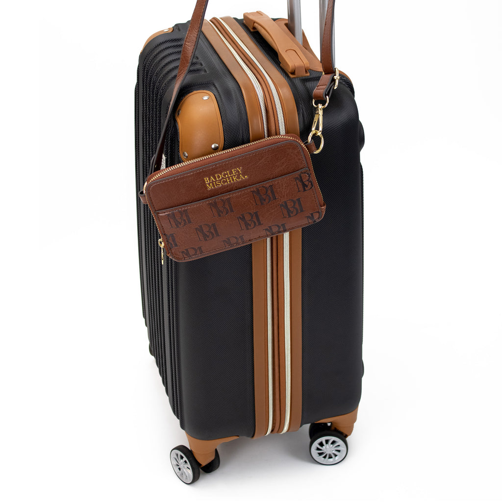 vegan leather monogram print badgley mischka purse on a luggage handle