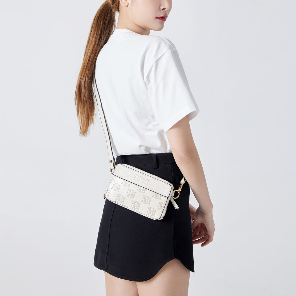 woman modeling the white vegan leather purse with shoulder strap by badgley mischka